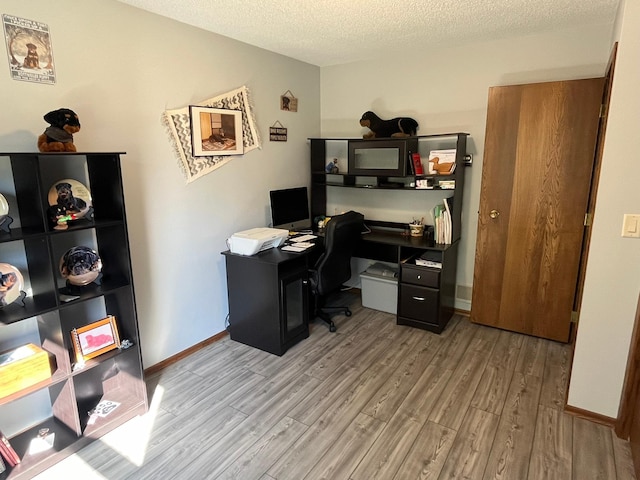 office area featuring light wood-type flooring and a textured ceiling