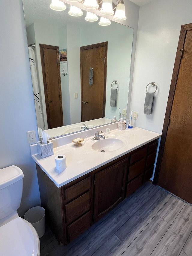 bathroom featuring hardwood / wood-style flooring, toilet, vanity, and a textured ceiling