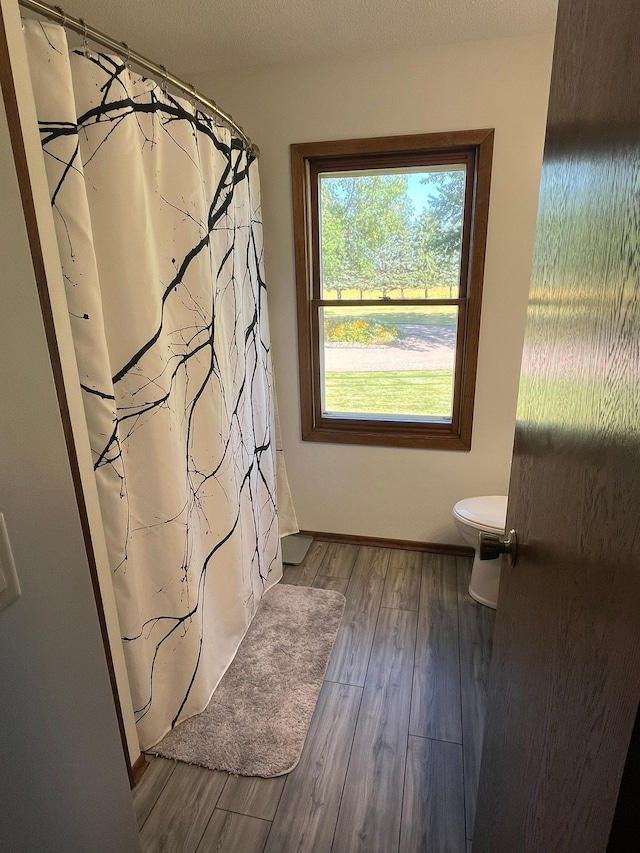 bathroom with walk in shower, hardwood / wood-style flooring, toilet, and a textured ceiling