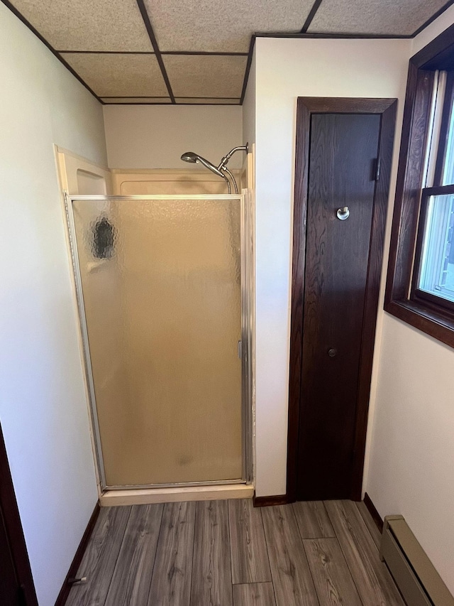 bathroom with baseboard heating, a paneled ceiling, hardwood / wood-style floors, and a shower with door