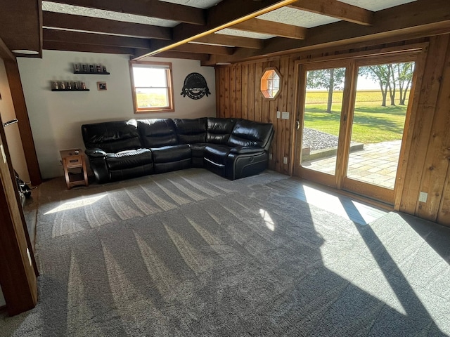 living room featuring carpet floors, wooden walls, and beam ceiling