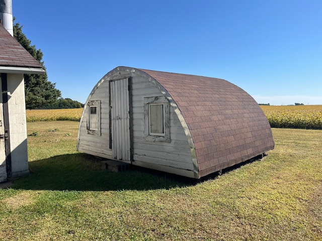 view of outbuilding featuring a rural view and a lawn