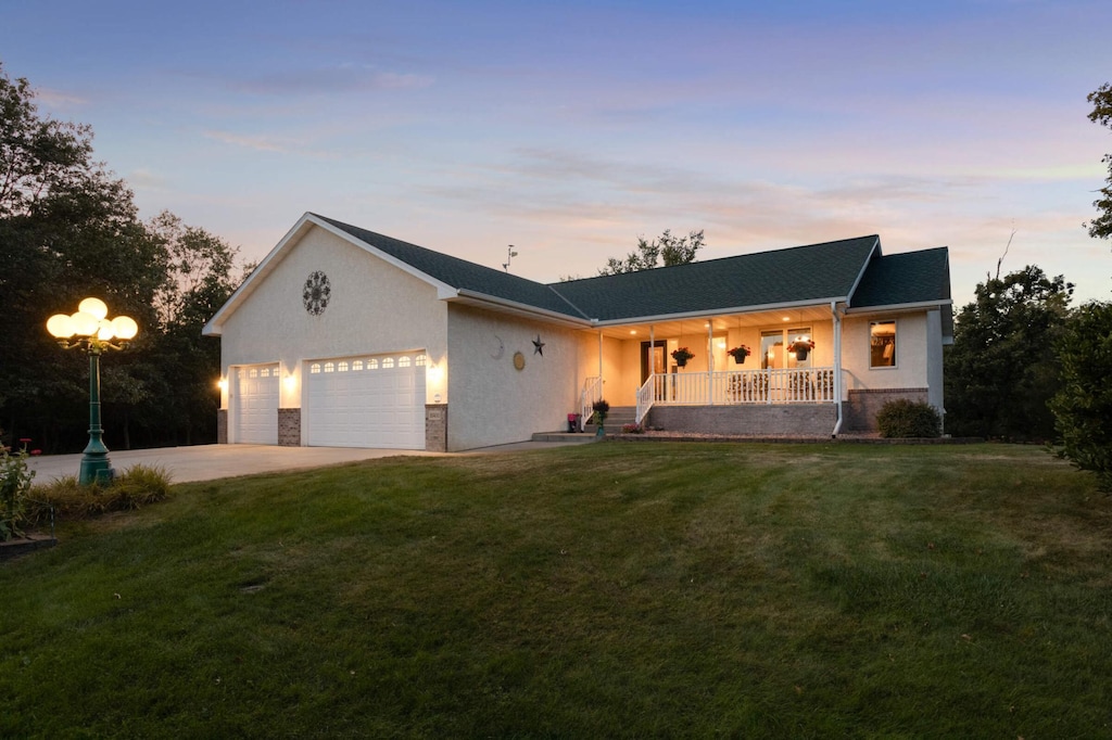 view of front of property featuring a lawn, a porch, and a garage