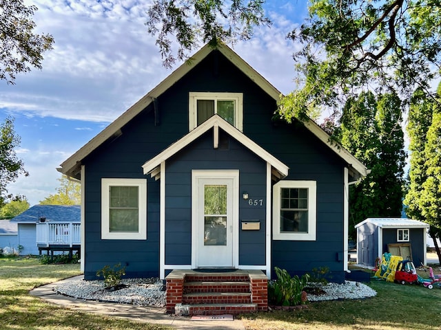 bungalow-style home with a shed and a front lawn