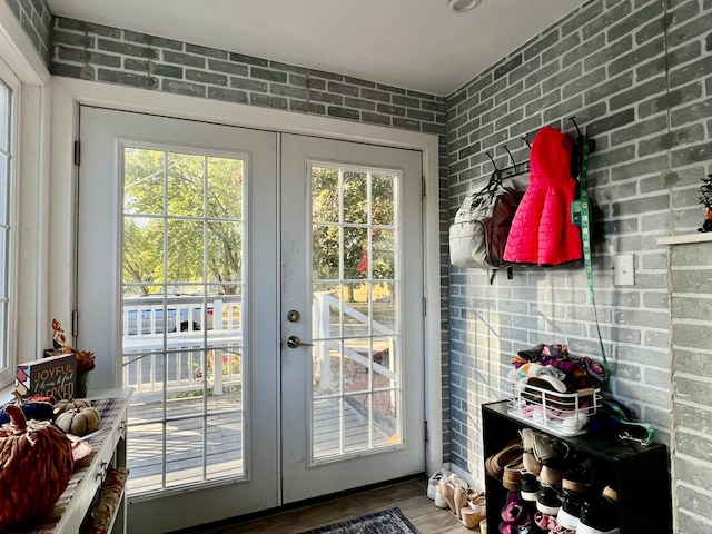 doorway to outside with a healthy amount of sunlight, wood-type flooring, brick wall, and french doors