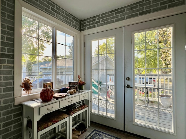 doorway with hardwood / wood-style flooring, french doors, and brick wall