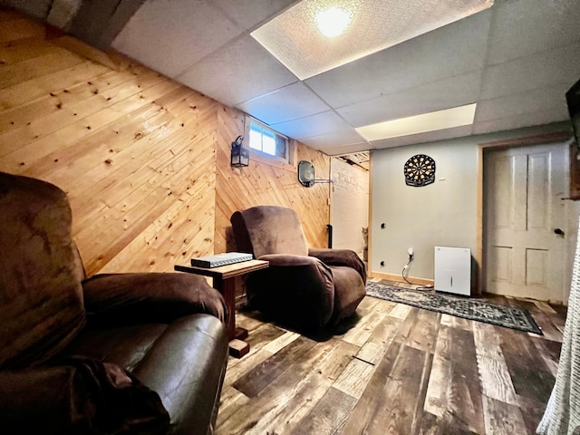 interior space with a drop ceiling, wood walls, and light hardwood / wood-style flooring