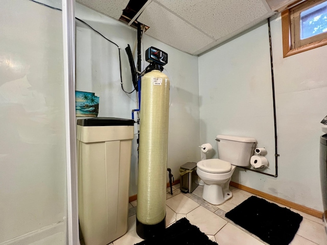 bathroom with a paneled ceiling, toilet, and tile patterned flooring