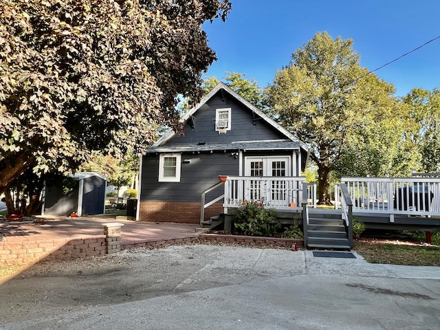 bungalow-style house with a storage shed and a wooden deck