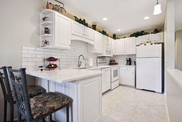 kitchen with pendant lighting, sink, white cabinets, kitchen peninsula, and white appliances