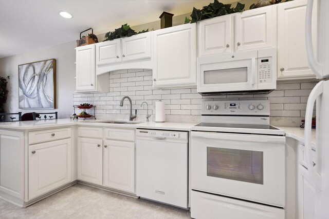 kitchen with backsplash, white appliances, white cabinetry, and sink