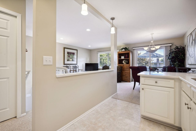 kitchen with pendant lighting, light carpet, and a healthy amount of sunlight