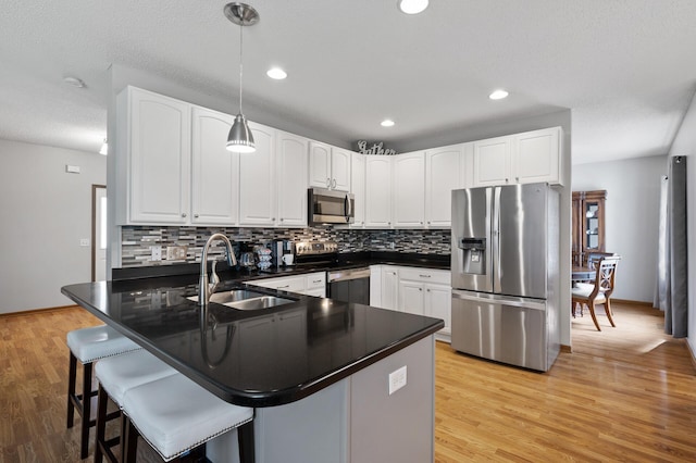 kitchen with sink, stainless steel appliances, hanging light fixtures, and white cabinets