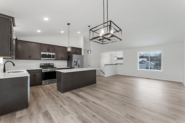 kitchen with sink, light wood-type flooring, decorative light fixtures, a kitchen island, and stainless steel appliances