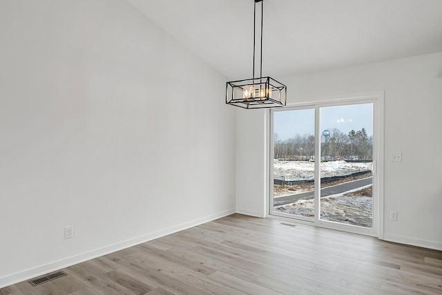 unfurnished dining area with a chandelier and light hardwood / wood-style floors