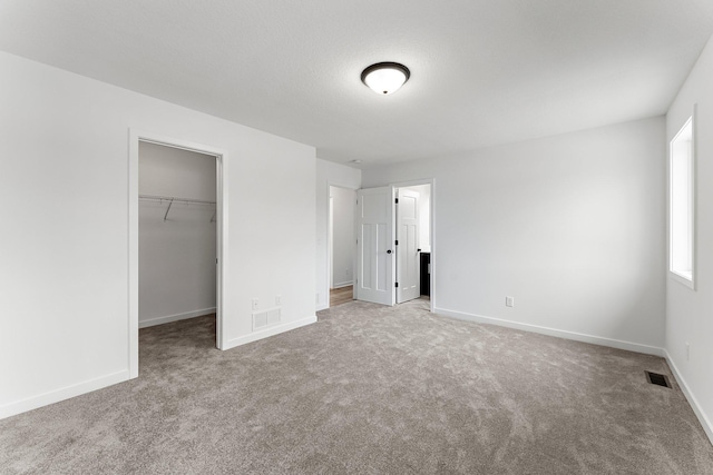 unfurnished bedroom with light colored carpet, a spacious closet, and a closet