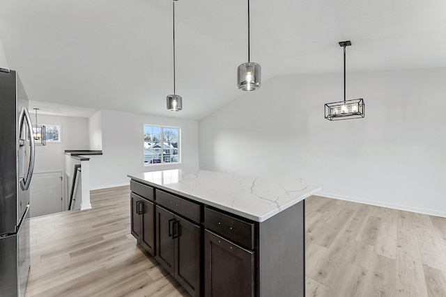 kitchen with stainless steel fridge, a center island, hanging light fixtures, and lofted ceiling