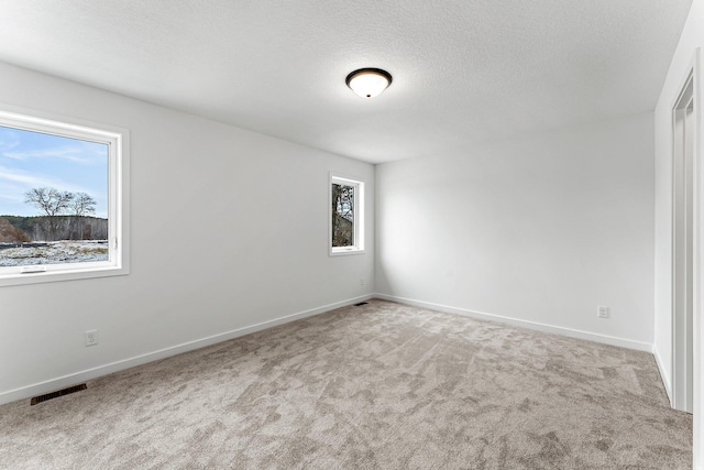 unfurnished room with a textured ceiling and light carpet