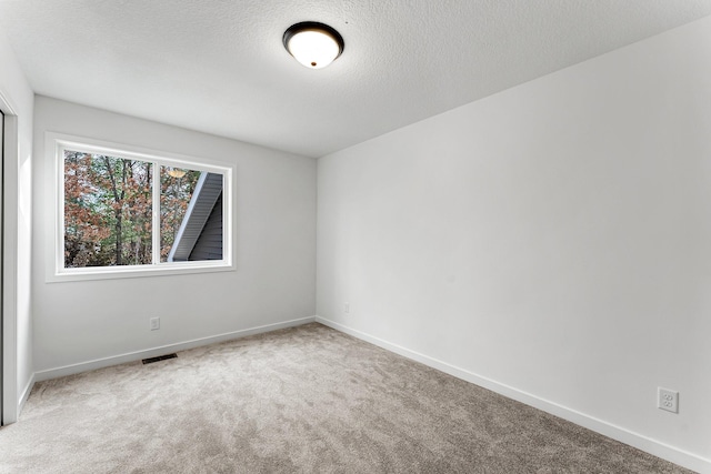 carpeted spare room featuring a textured ceiling