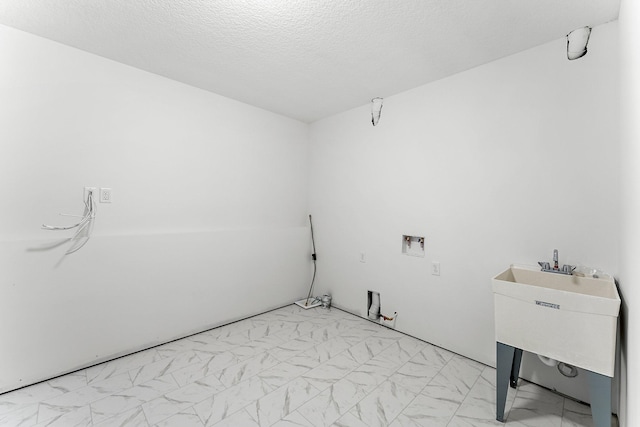 washroom featuring a textured ceiling, sink, and hookup for a washing machine