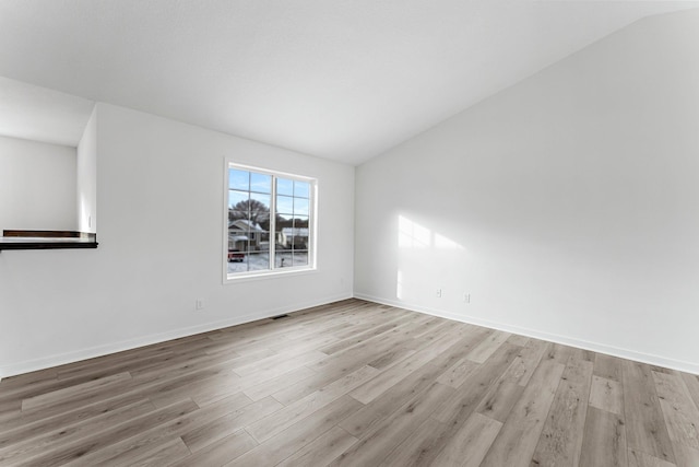 empty room with vaulted ceiling and light hardwood / wood-style flooring