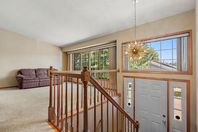 entrance foyer with carpet floors, an inviting chandelier, and a textured ceiling