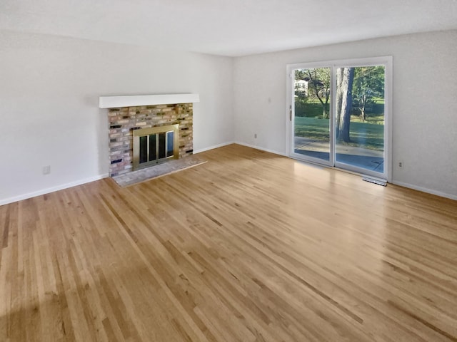 unfurnished living room with light hardwood / wood-style flooring and a brick fireplace