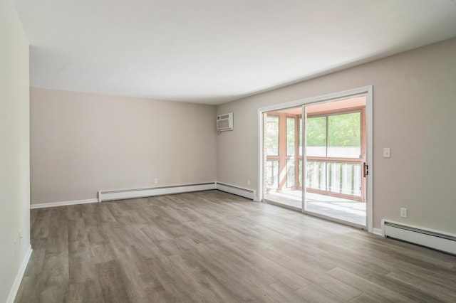 spare room with wood-type flooring, a baseboard radiator, and a wall mounted AC