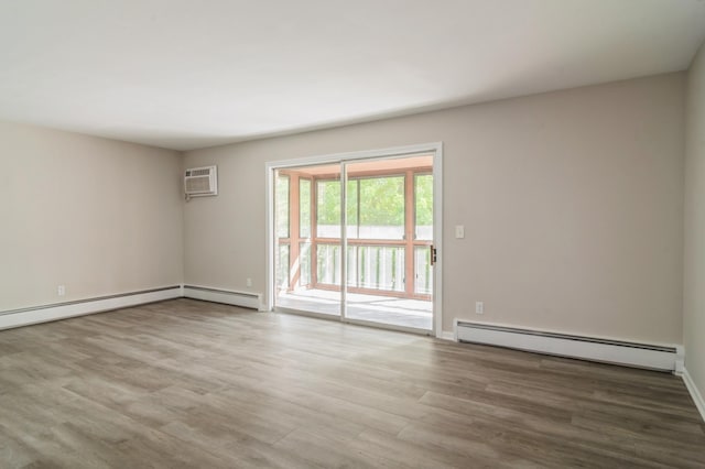 spare room with a wall mounted AC, hardwood / wood-style floors, and a baseboard heating unit