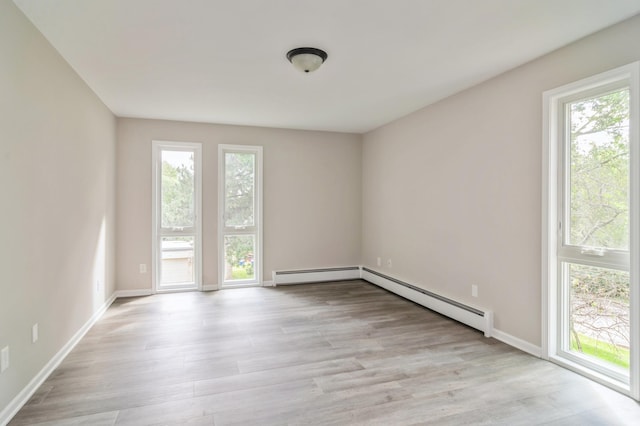 spare room with light hardwood / wood-style floors, a baseboard heating unit, and plenty of natural light