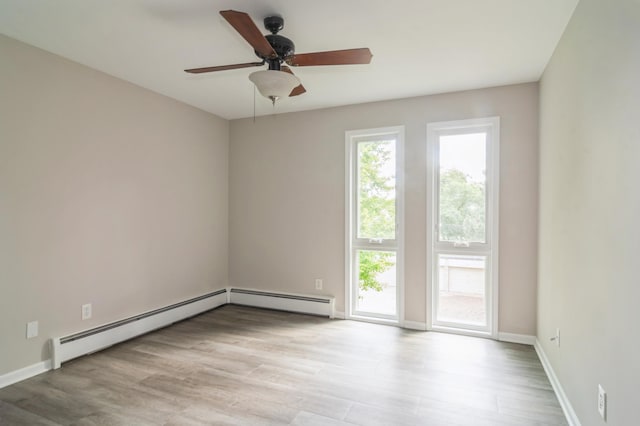 empty room with ceiling fan, light wood-type flooring, and a baseboard heating unit