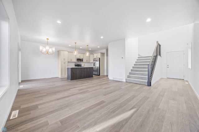 unfurnished living room with a chandelier, light wood finished floors, stairway, recessed lighting, and baseboards