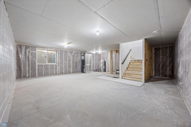 below grade area featuring water heater, stairway, concrete block wall, and heating unit