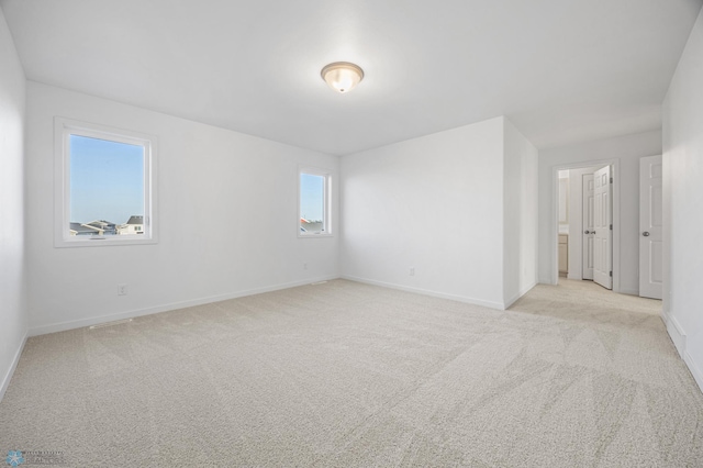 unfurnished room featuring baseboards and light colored carpet