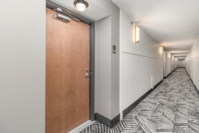 corridor with a textured ceiling and baseboards