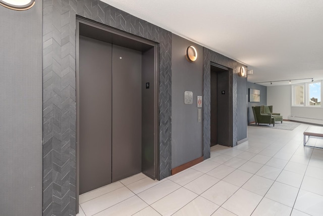 corridor featuring light tile patterned floors, elevator, and baseboard heating