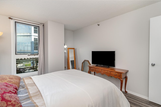 bedroom featuring a textured ceiling, baseboards, and wood finished floors