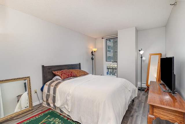 bedroom with a baseboard heating unit, baseboards, and wood finished floors