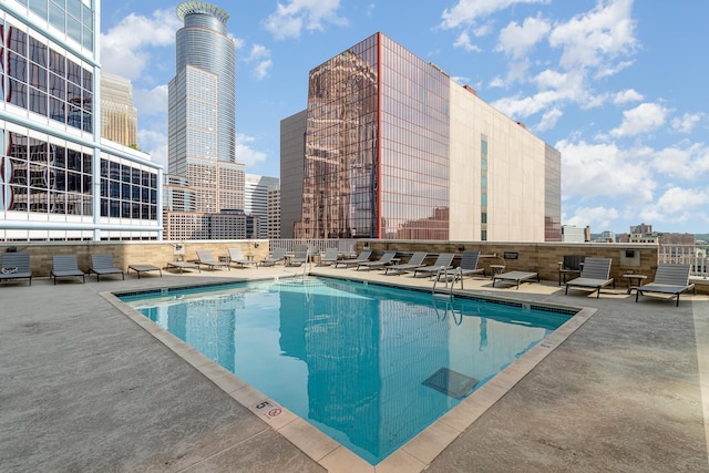 pool with fence, a city view, and a patio area