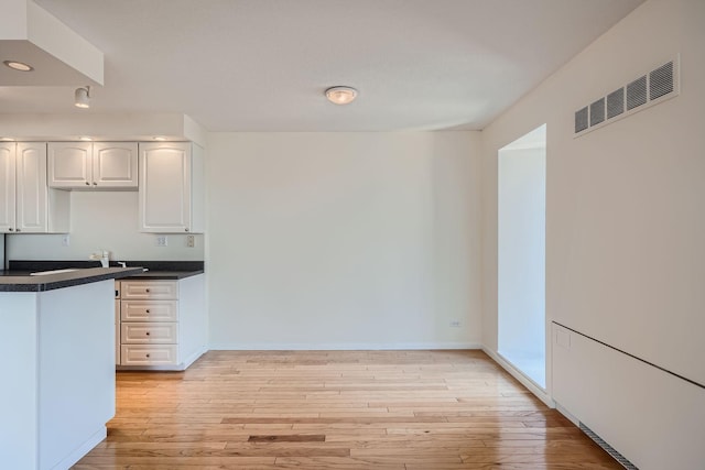 kitchen with light hardwood / wood-style flooring and white cabinetry