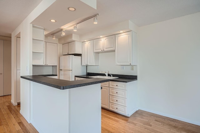 kitchen with kitchen peninsula, white cabinetry, white refrigerator, and light hardwood / wood-style floors