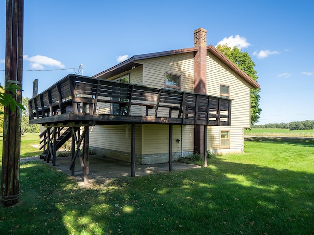 back of property featuring a wooden deck, a patio, and a yard