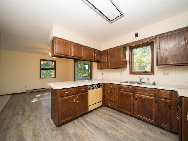 kitchen featuring light hardwood / wood-style floors, kitchen peninsula, white dishwasher, ceiling fan, and a baseboard radiator