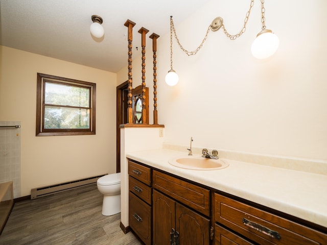 bathroom with a baseboard heating unit, hardwood / wood-style floors, vanity, and toilet