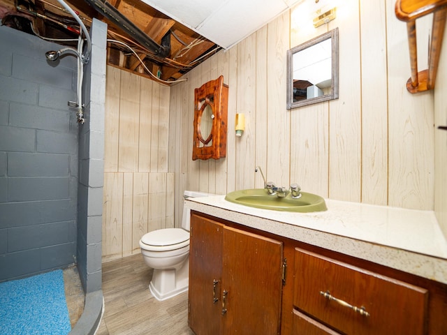 bathroom with wood walls, hardwood / wood-style flooring, vanity, and toilet