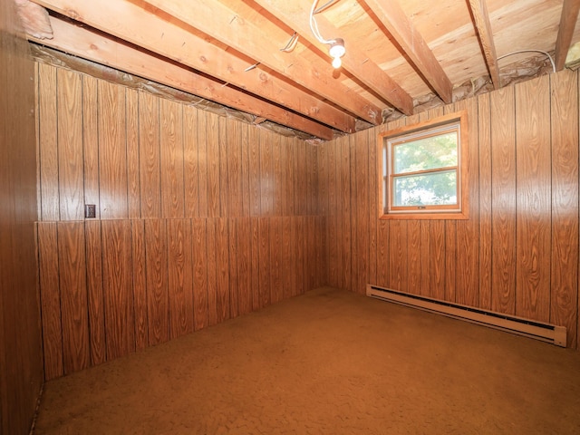 basement featuring wood walls and a baseboard heating unit