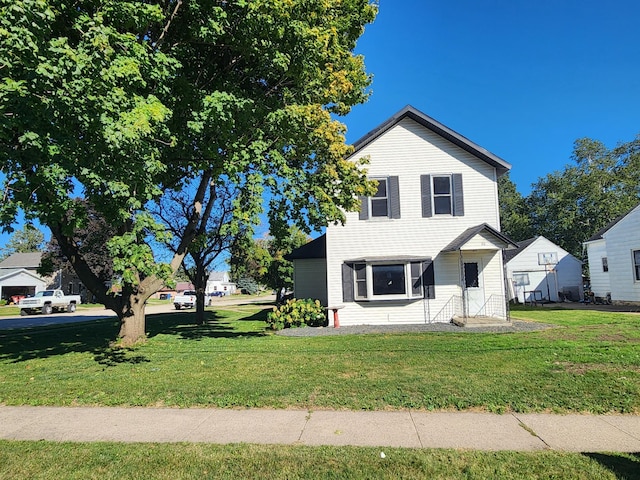 view of front of house with a storage shed and a front lawn