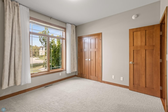 unfurnished bedroom featuring multiple windows, carpet flooring, and a closet