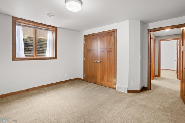 unfurnished bedroom with light colored carpet and a closet