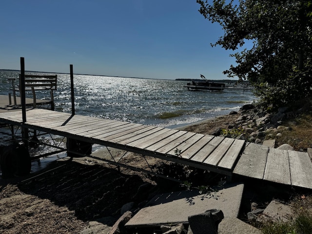 view of dock with a water view and a beach view